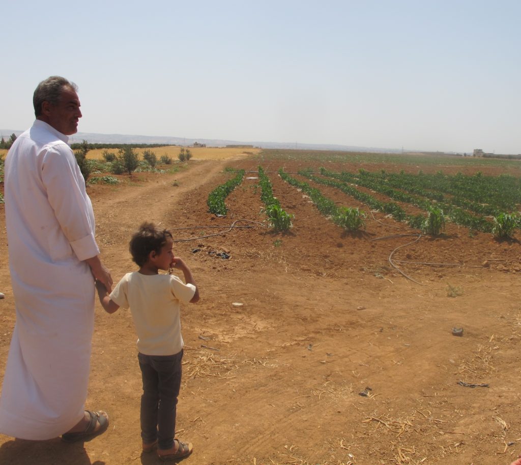 A man and boy showing Medair staff the farm they're working in in Jordan