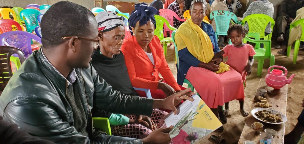 A group of women and one man looking at a Tearfund booklet