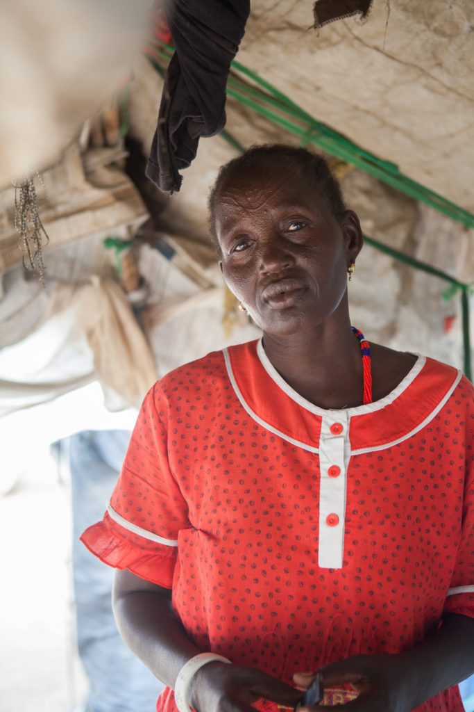 A woman in a red dress in South Sudan looking at the camera