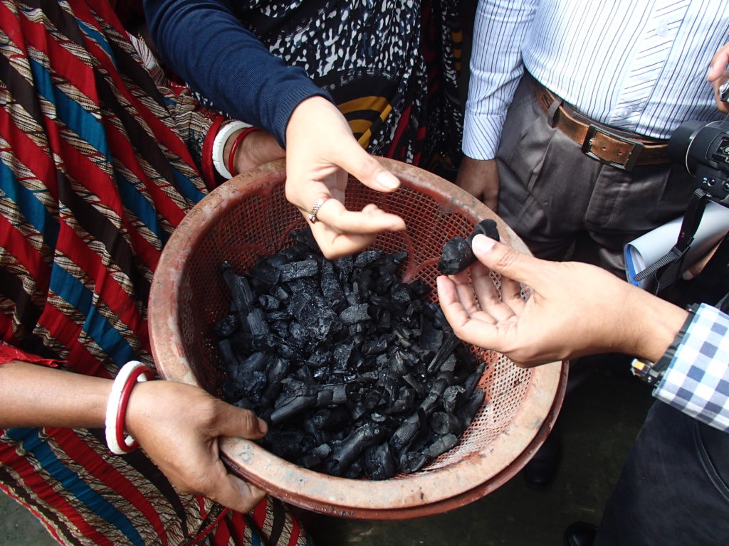 A bowl of coal with people holding and then passing it to others