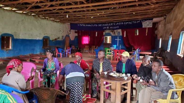 A group of men and women in a church in Ethiopia, sharing food and drink